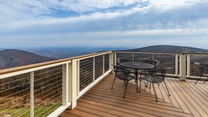 Une terrasse avec une table et des chaises donnant sur un paysage montagneux.