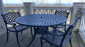 A round metal table with four chairs on a wooden deck with railings. - Shenandoah Ridge 07 with Wintergreen Advantage (Wintergreen)