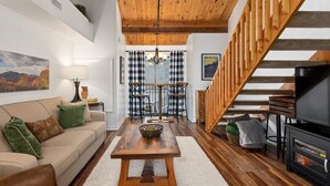 A cozy living room with a wooden ceiling, a sofa with green cushions, a coffee table, and a TV stand. - Mountain Inn Lodge 55 with Wintergreen Advantage (Wintergreen)