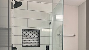 Un baño moderno con ducha de vidrio, inodoro y salpicadero de azulejos estampados.