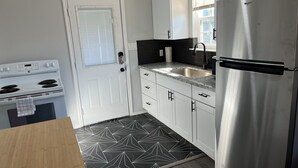 Una cocina moderna con armarios blancos, un refrigerador de acero inoxidable, horno integrado y un salpicadero con estampado blanco y negro.