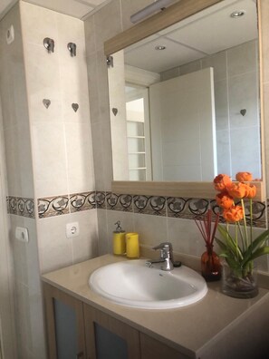 Ein Badezimmer mit einem weißen Waschbecken, einem Spiegel und einer dekorativen Fliesenbordüre.