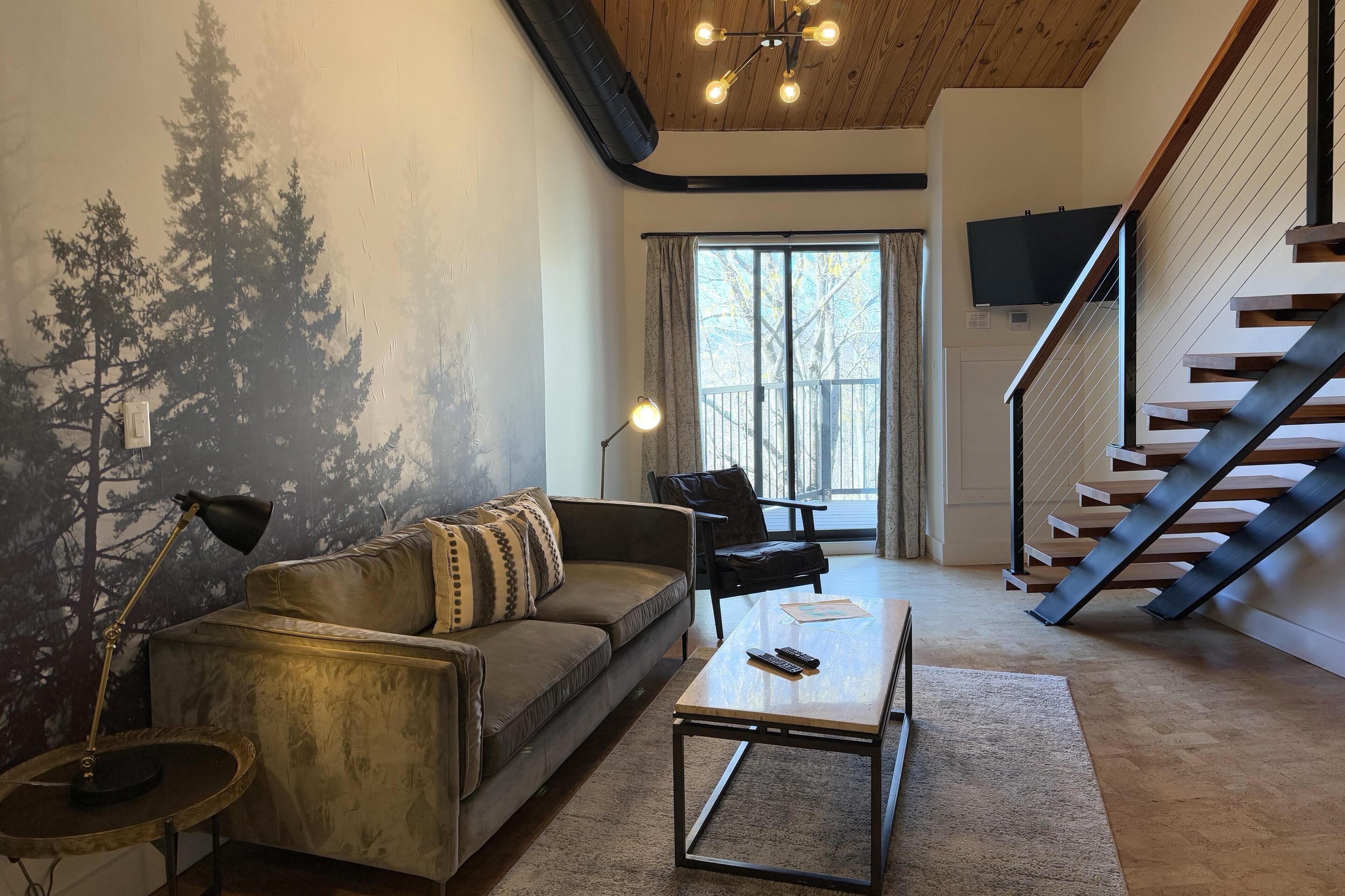 Una sala de estar con un sofá, una mesa de centro y una escalera.