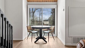 A dining area with a round table and four chairs, a wooden ceiling, and a view through a window with blinds. - Mountain Inn Lodge 71 with Wintergreen Advantage (Wintergreen)
