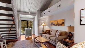 A spacious living area with a staircase, a sofa, a coffee table, and a painting on the wall. - Mountain Inn Lodge 82 with Wintergreen Advantage (Wintergreen)