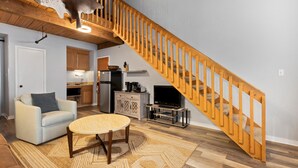 A living room with a wooden staircase, a sofa, a coffee table, and a television. - Mountain Inn Lodge 83 with Wintergreen Advantage (Wintergreen)