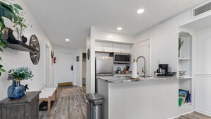 A modern kitchen with white cabinets, a stainless steel refrigerator, a microwave, and a coffee machine. - Timbers Lodge 39 with Wintergreen Advantage (Wintergreen)