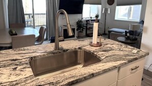 A kitchen with a granite countertop, stainless steel sink, and a wooden stand. - Timbers Lodge 39 with Wintergreen Advantage (Wintergreen)