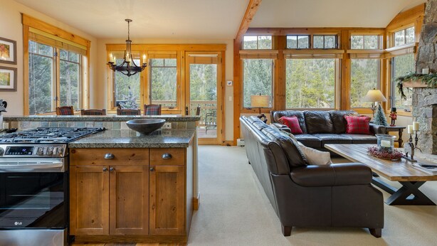 A spacious kitchen with wooden cabinets, a large island, and a dining area with a sofa and table. - Stunning Townhome with Great Views (Keystone)