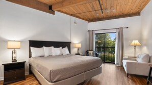 A bedroom with a large bed, wooden flooring, a balcony with a view, and a white sofa. - Mountain Inn Studio 92 with Wintergreen Advantage (Wintergreen)