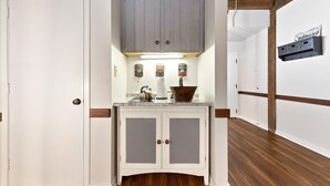 A hallway with a white door, a wooden floor, a white cabinet with two doors, a gray cabinet above, and a wall-mounted shelf with a sign. - Mountain Inn Studio 97 with Wintergreen Advantage (Wintergreen)