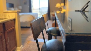 A hotel room with a bed, a desk, and a chair. There is a window with a view of the outside.