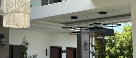 Un edificio moderno con un balcone in vetro, ringhiere in metallo e lampade a sospensione.