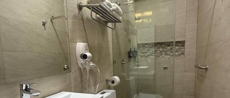 Un baño moderno con cabina de ducha de vidrio, lavamanos blanco y un inodoro.