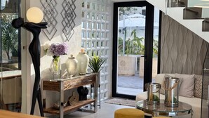 A modern living room with a glass coffee table, a sofa, and a decorative console table with vases and plants. - Hotel Tepeu (Flores)