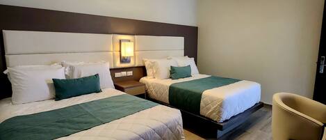 A hotel room with two beds, a ceiling fan, an air conditioner, and a chair.