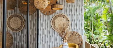 A modern interior with woven pendant lights, a round wooden table, and a yellow chair.