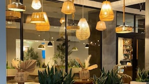 A restaurant with hanging wicker lamps, potted plants, and a modern interior design. - Hotel Tepeu (Flores)