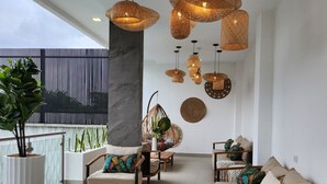 A modern lounge area with wicker pendant lighting, cushioned seating, and a potted plant. - Hotel Tepeu (Flores)