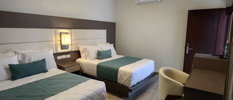 Una habitación de hotel con dos camas, ventilador de techo, aire acondicionado y piso de madera.