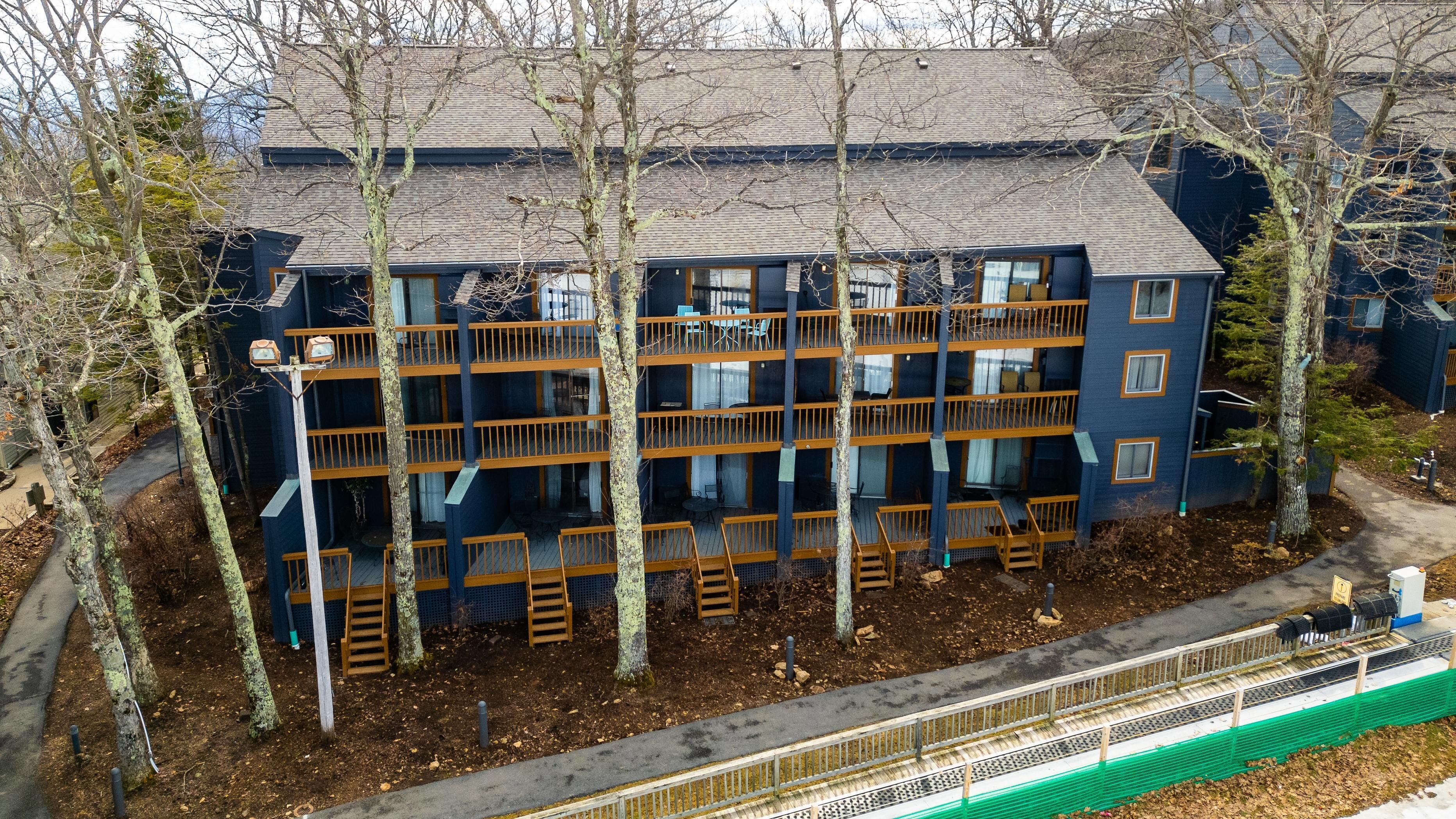 A multi-story building with balconies, surrounded by trees.