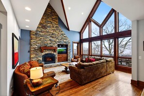A spacious living room with a stone fireplace, large windows, and a cozy seating area. - Blue Ridge Retreat with Wintergreen Advantage (Wintergreen)
