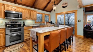 Una cocina con armarios de madera, electrodomésticos de acero inoxidable y una isla grande con taburetes de bar.