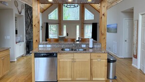Une cuisine avec des meubles en bois, un lave-vaisselle et un plan de travail en granit.