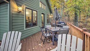 Een groene houten woning met een terras, buitenmeubels en uitzicht op een bos.