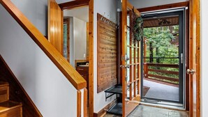 A wooden staircase leading to a room with a wooden door and a view of greenery outside.