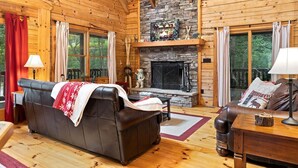 L’intérieur d’une cabane en rondins, avec une cheminée, un canapé en cuir et un plancher en bois.