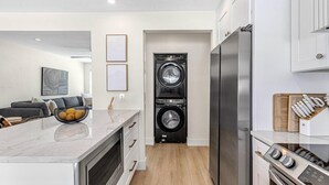A modern kitchen with a built-in washer and dryer, stainless steel appliances, and a marble countertop.