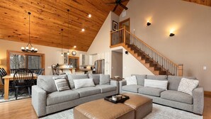 A spacious living room with a large gray sectional sofa, a tan ottoman, and a wooden ceiling. - Chestnut Springs with Wintergreen Advantage (Wintergreen)