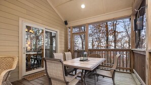 A covered patio with a table and chairs, large windows, and a wooden deck. - Chestnut Springs with Wintergreen Advantage (Wintergreen)