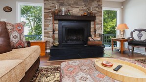 Una sala de estar con chimenea, un sofá, una mesa de centro y vistas al exterior.