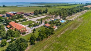 An aerial view of a rural property with multiple buildings, a swimming pool, and surrounding fields.