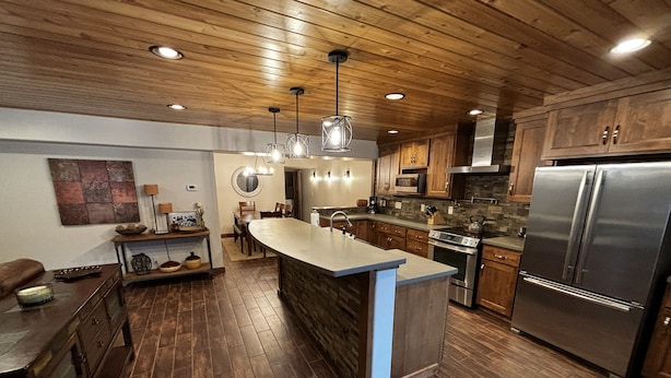 A modern kitchen with wooden cabinets, a central island, stainless steel appliances, and pendant lighting. - Luxury condo perfectly located in Cavanaugh Bay! Fully furnished!  (Coolin)