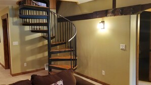 A spiral staircase with wooden steps and black railings in a room with beige walls and a carpeted floor. - Luxury condo perfectly located in Cavanaugh Bay! Fully furnished!  (Coolin)