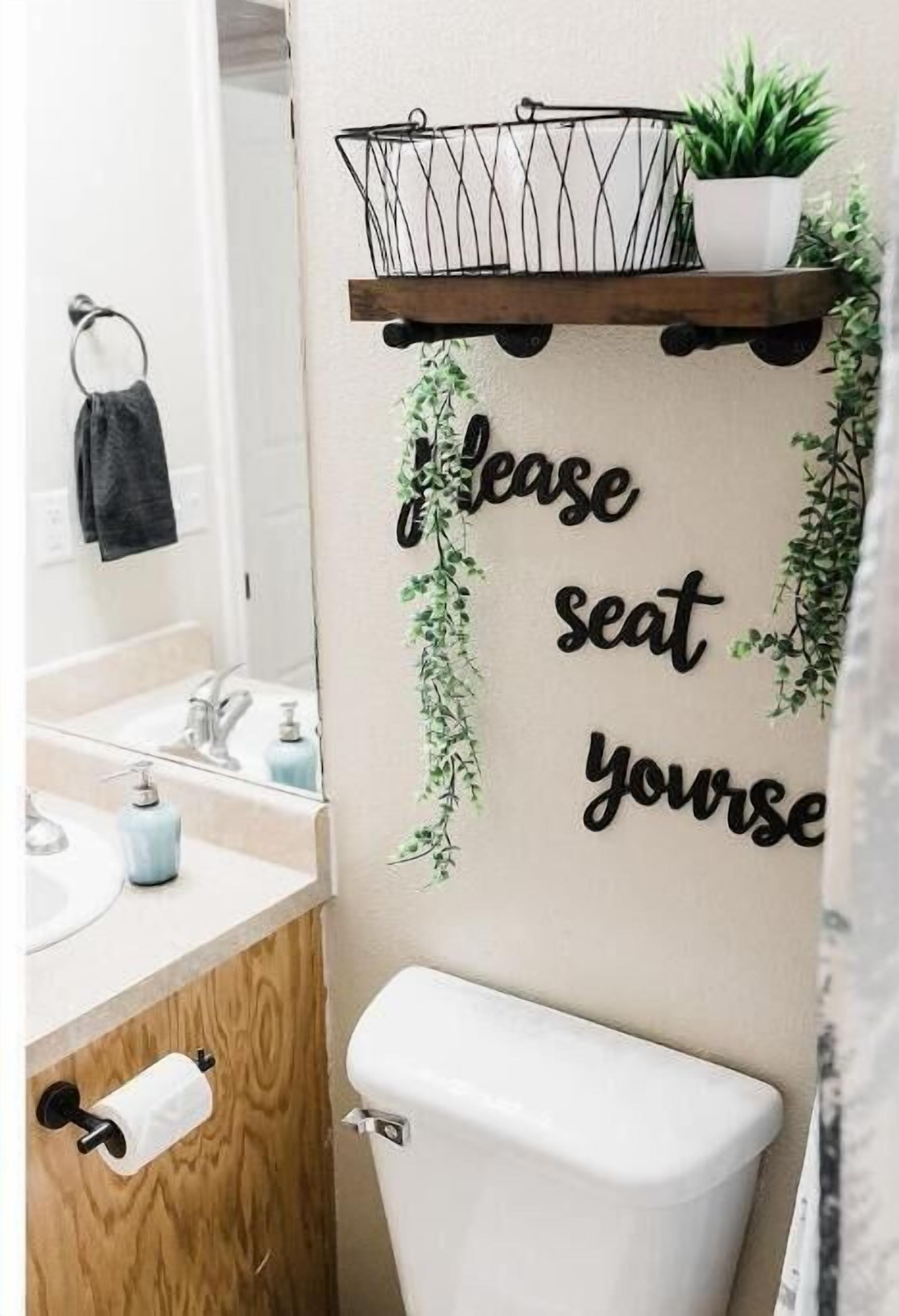 A bathroom with a toilet, sink, and a wall-mounted shelf with a plant.