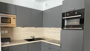 A modern kitchen with grey cabinets, a black countertop, a built-in microwave, and a built-in oven.