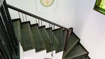 A staircase with a handrail, a wall-mounted picture, and a window with a green frame.