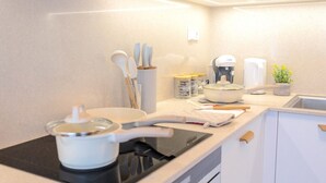 Une cuisine moderne équipée d’une cuisinière, de casseroles, d’ustensiles et d’une machine à café.