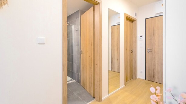 Un couloir avec des portes en bois et un espace douche.