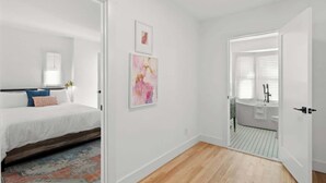A bedroom with a bed, a nightstand, and a wall-mounted lamp. - Spacious Detroit Retreat • Sleeps 16 • Parking (Detroit)
