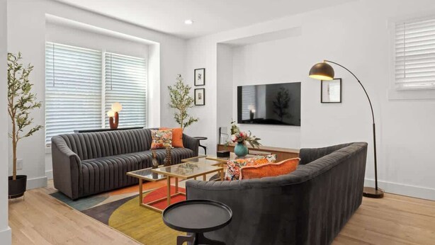 A modern living room with a sofa set, a coffee table, and a floor lamp. - Spacious Detroit Retreat • Sleeps 16 • Parking (Detroit)