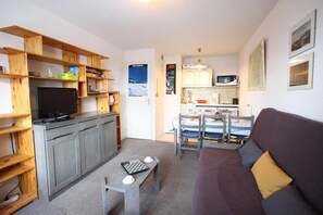 Een ruimtelijke leefruimte met een kitchenette, een eethoek en een zithoek.