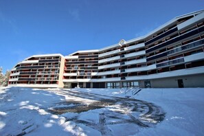 Een meerlaags hotel met balkons en een met sneeuw bedekte grond.