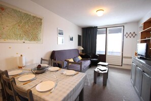 Een hotelkamer met een eettafel gedekt voor vier personen, een bank, een televisie en een grote kaart aan de muur.