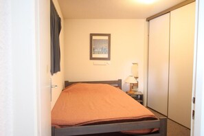 Een eenpersoonsbed in een kamer met nachtkastje, lamp en een ingelijst foto aan de muur.