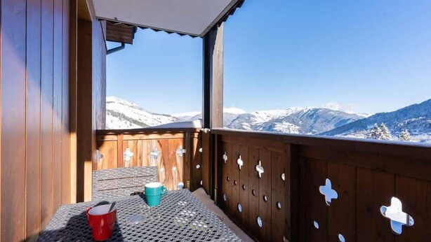 Un balcon avec une table, une tasse rouge et une tasse bleue.